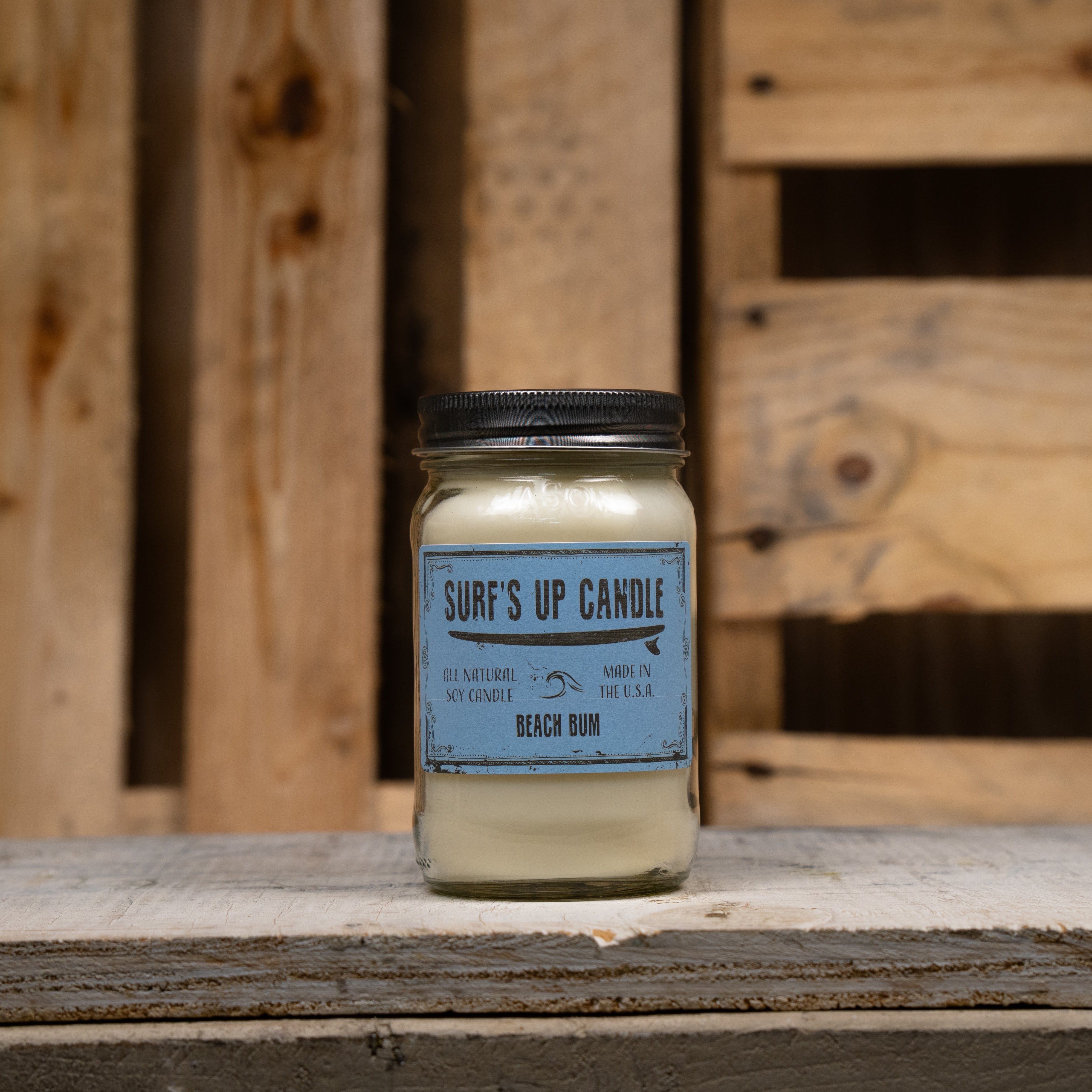 Candle labeled 'Beach Bum' on a wooden surface with a wooden crate background