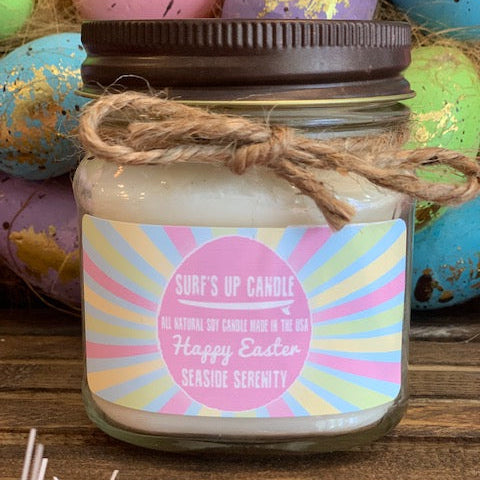 Candle in a jar with a colorful label on a wooden surface with Easter eggs in the background.